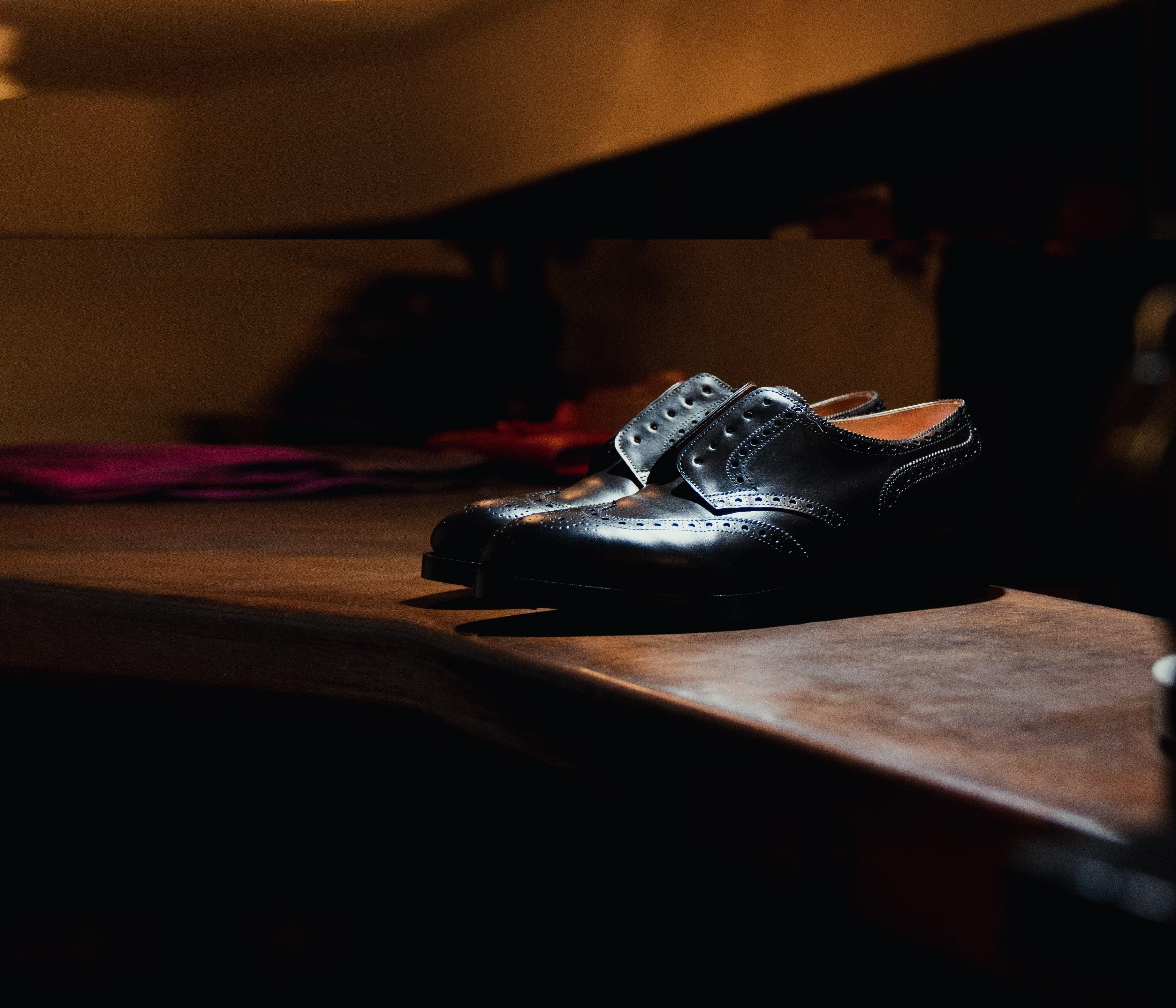 Warsztat — buty na drewnianym blacie, ciepłe światło kierunkowe